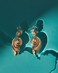 The Luv Aj Palma Shell Statement Earrings in Gold on blue background View 3