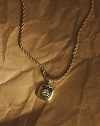 The Luv Aj Luna Bezel Pendant Necklace in Gold on a crinkled paper background View 4