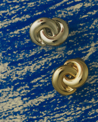The Luv Aj Solstice Knot Studs in Gold on blue background View 3